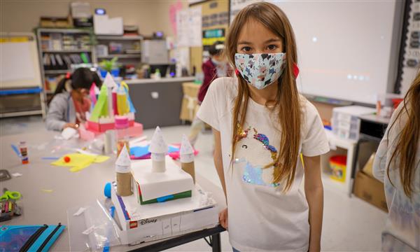 Student holds up a castle made out of recycled materials